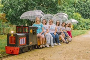 Amélie et sa team installées sur le petit train du Jardin Botanique avec leurs parapluies pour un souvenir insolite d'EVJF