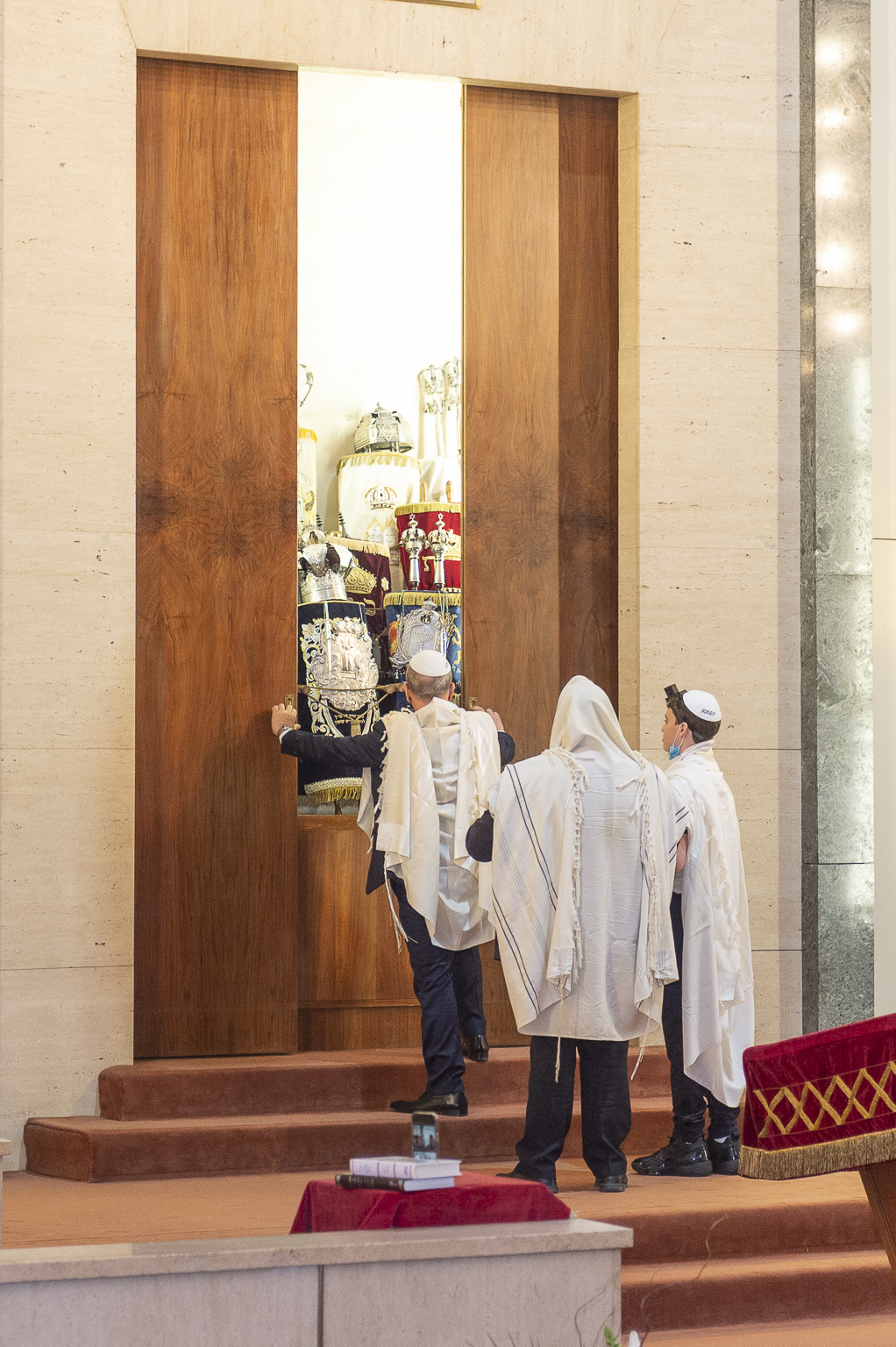 Hommes en talit et kippa ouvrant l'Arche sainte de la synagogue devant les rouleaux de la Torah